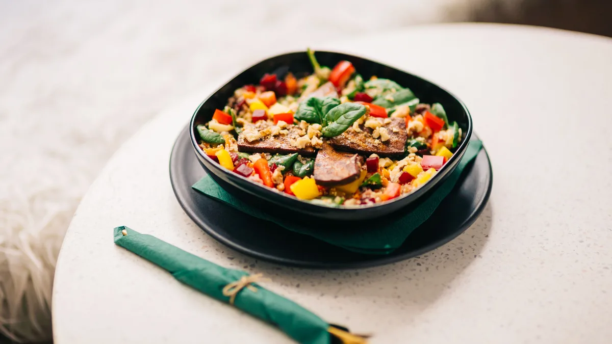 Siyah kase içinde renkli sebze, tahıl ve protein kaynaklarından oluşan dengeli bir öğün, üstten çekim