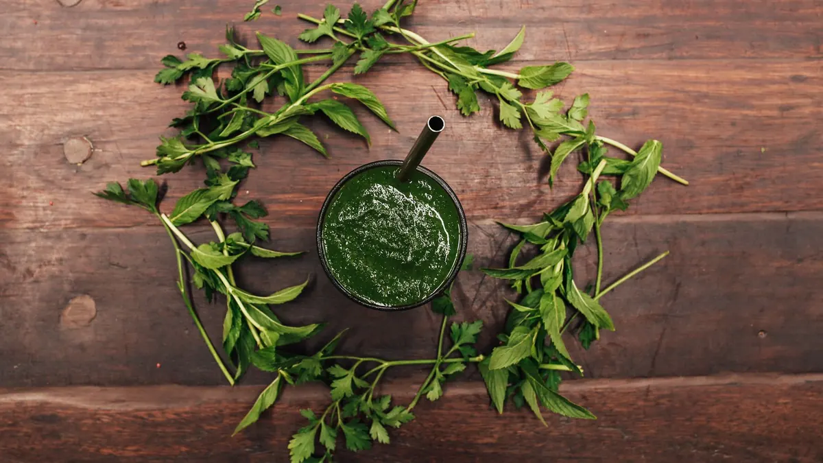 Yeşil smoothie, taze meyve ve yeşil yapraklı sebzelerin bulunduğu bir düzen